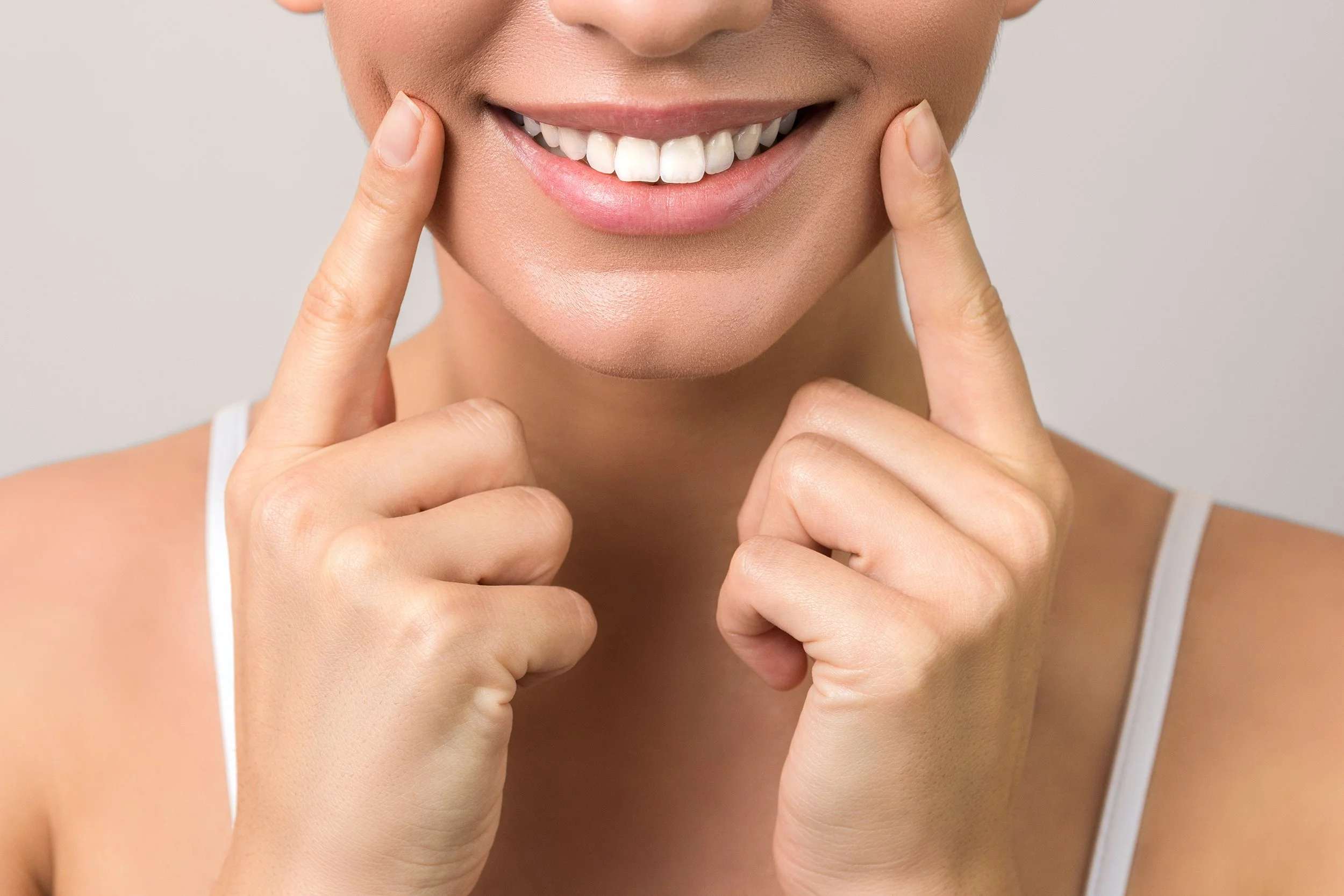 Woman smiling with white teeth. Whitening or veneers — which is right for your smile? Learn what each treatment does, where each falls short, and how to choose based on your actual goals.