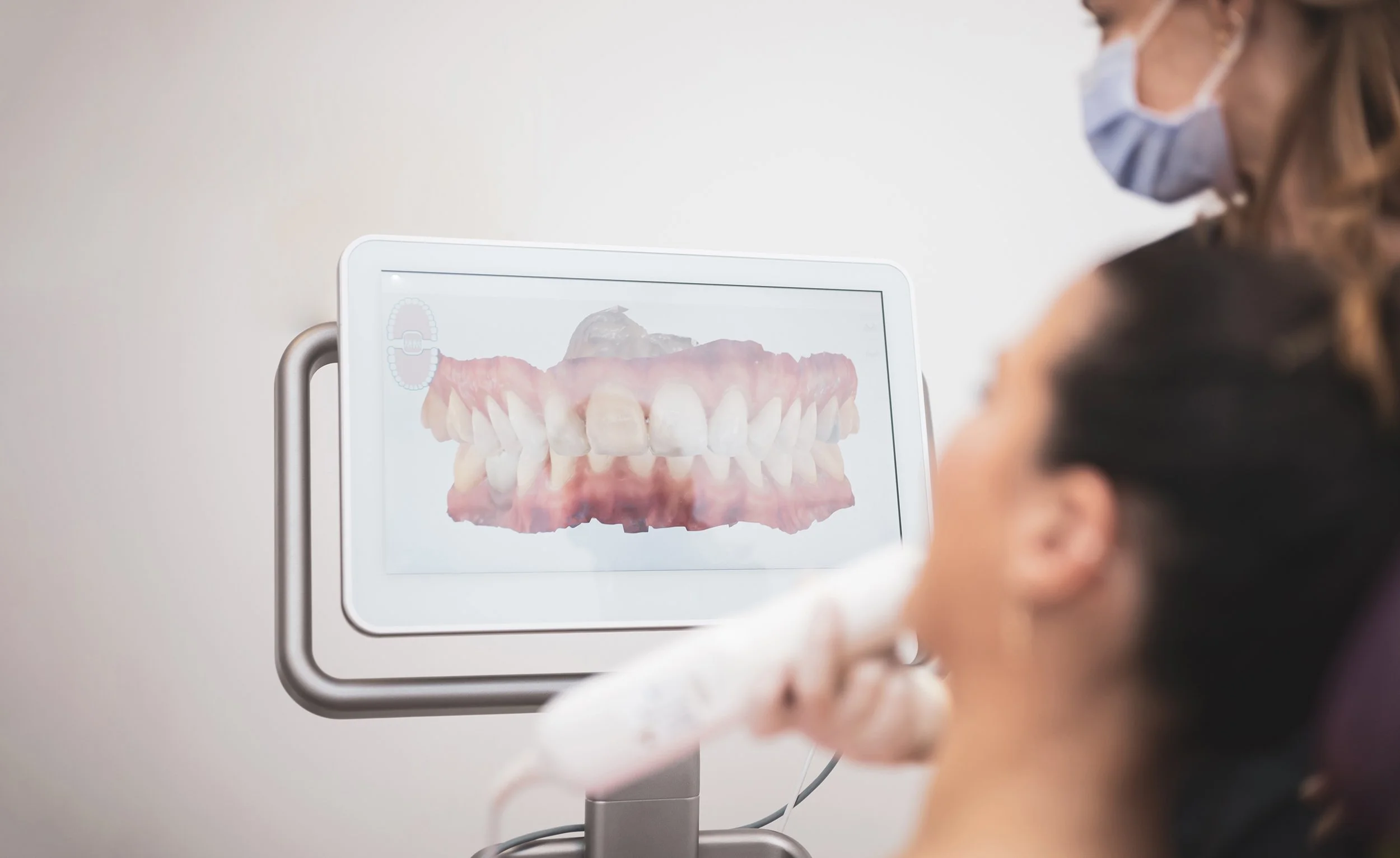 A woman watches her teeth on a high-resolution screen showing detailed pictures of her mouth. AI in dentistry isn't some future scenario. It's here now. Read more in our guide.