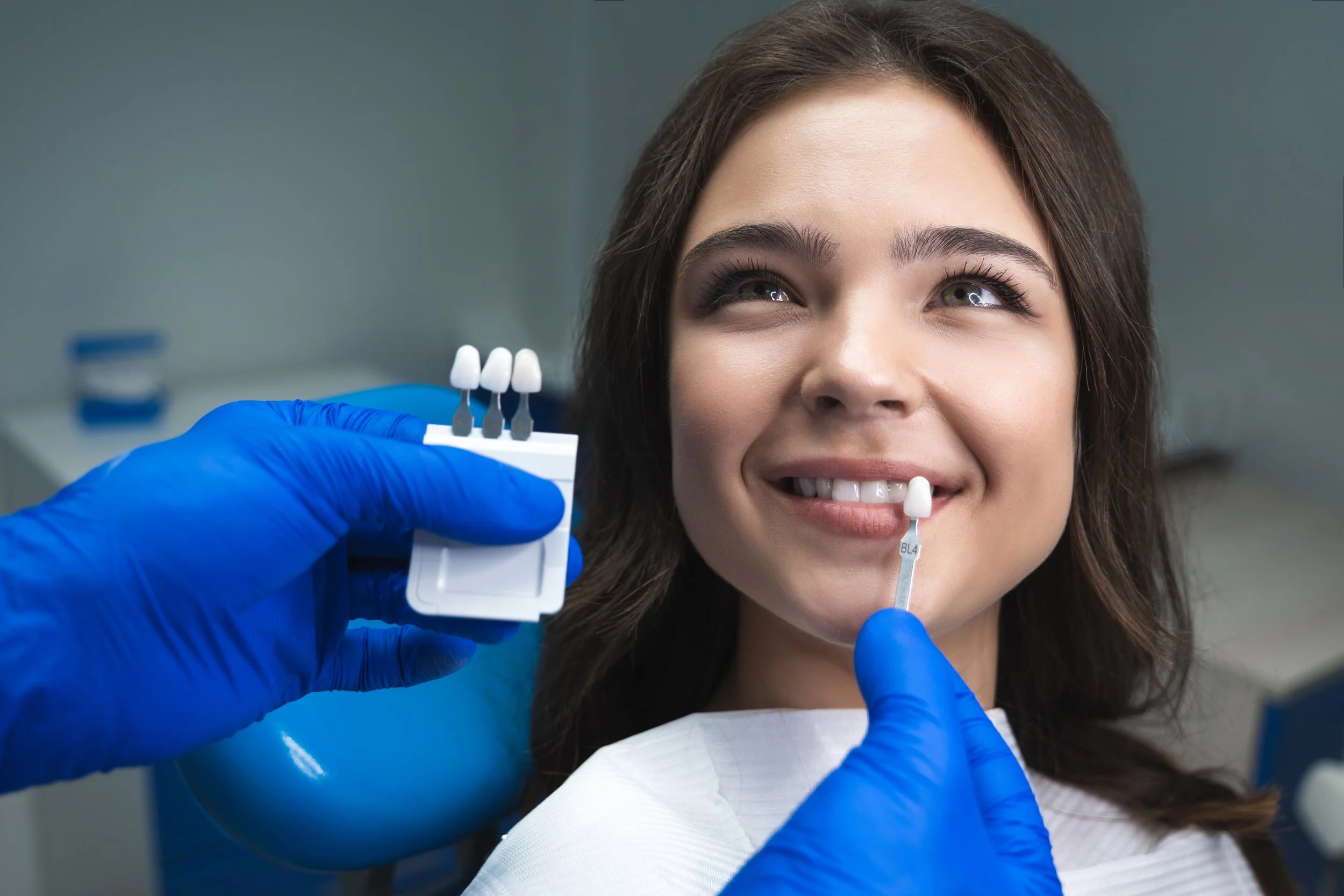 Woman in dentist chair. Teeth whitening and veneers solve different problems. Here's how to tell which treatment actually addresses what's bothering you about your smile.