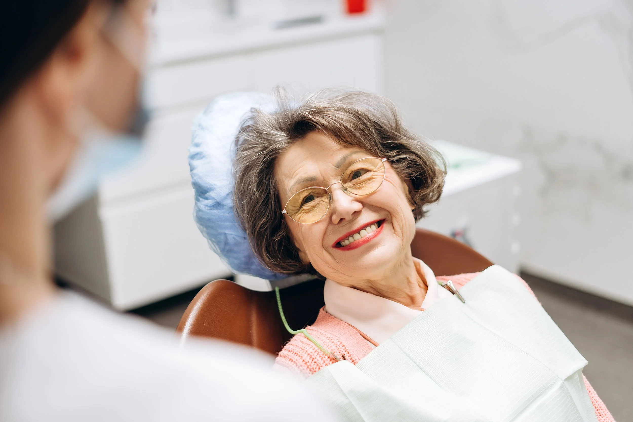 A woman smiles from a dental chair. Discover minimally invasive dentistry techniques that detect problems early, preserve healthy teeth, and reduce treatment time with modern dental technology.