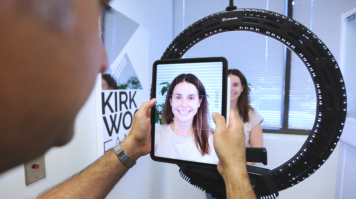 A woman gets her before smile picture taken at Kirkwood Family Dental.