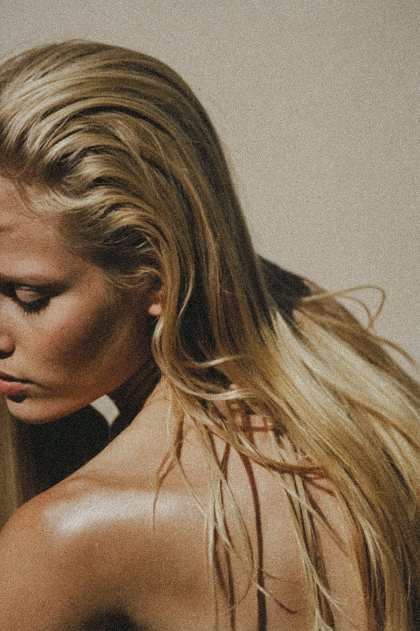 Close-up of a person with long blonde hair and sunlight on their shoulder.