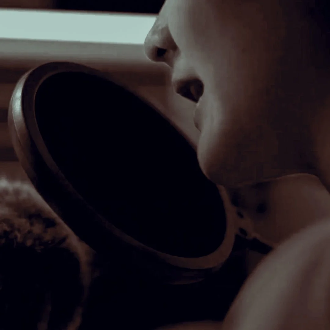 Nahaufnahme einer Person beim Singen oder Sprechen vor einem Mikrofon.