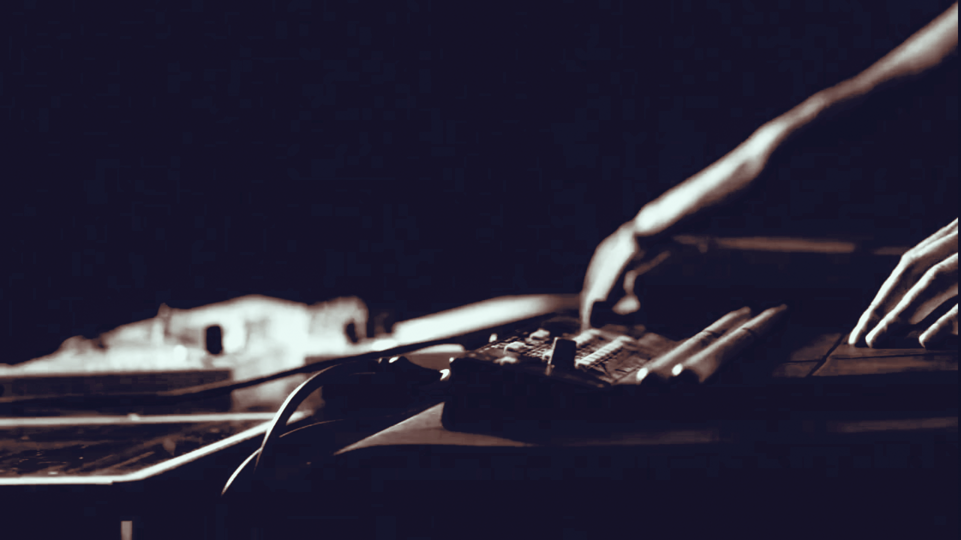 Nahaufnahme eines Klaviers mit einer Hand, die auf die Tasten spielt, in dunklem Licht