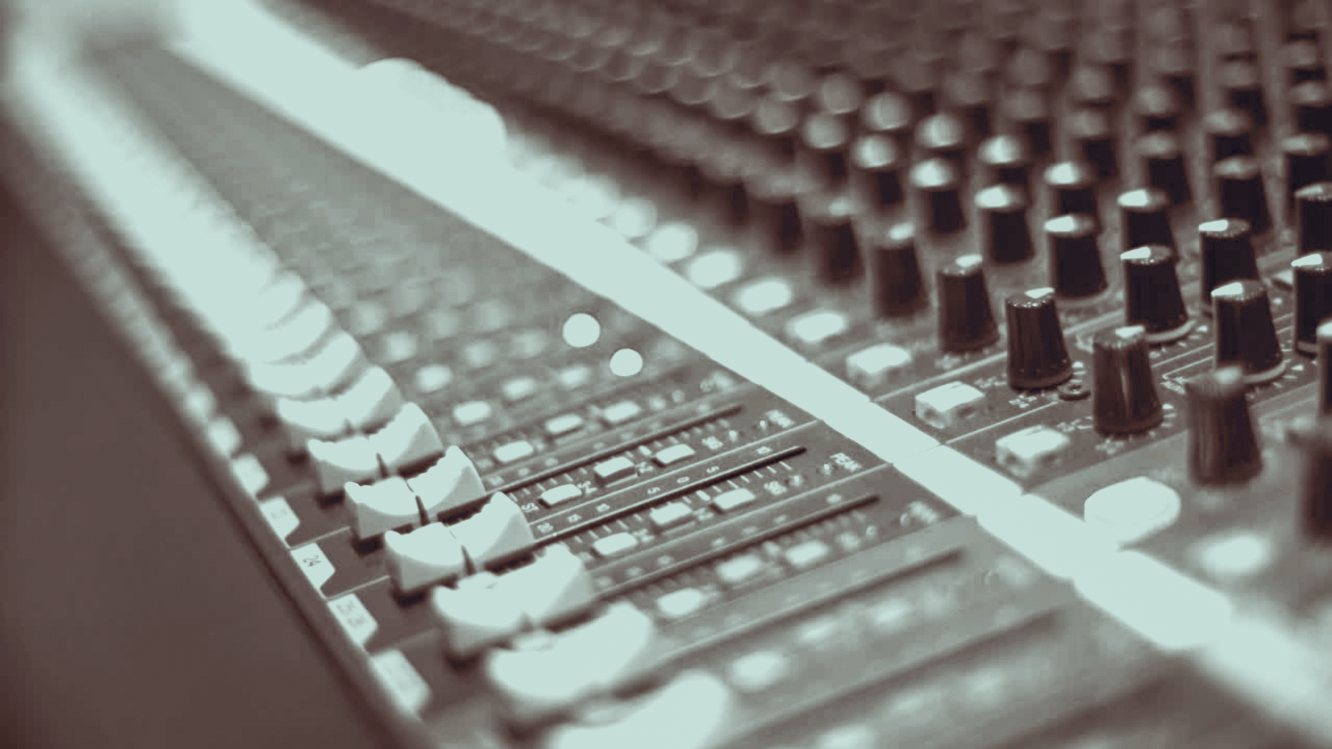 Nahaufnahme eines Mischpults mit Reglern und Schiebereglern.