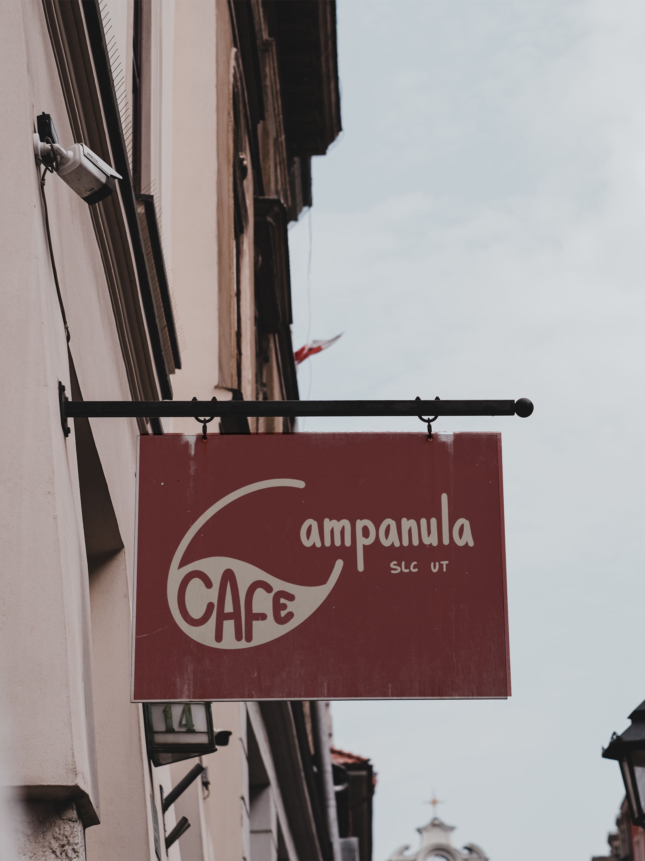 Red sign hanging outside a cafe with the words 'Campanula Cafe' and 'SLC UT' printed on it.