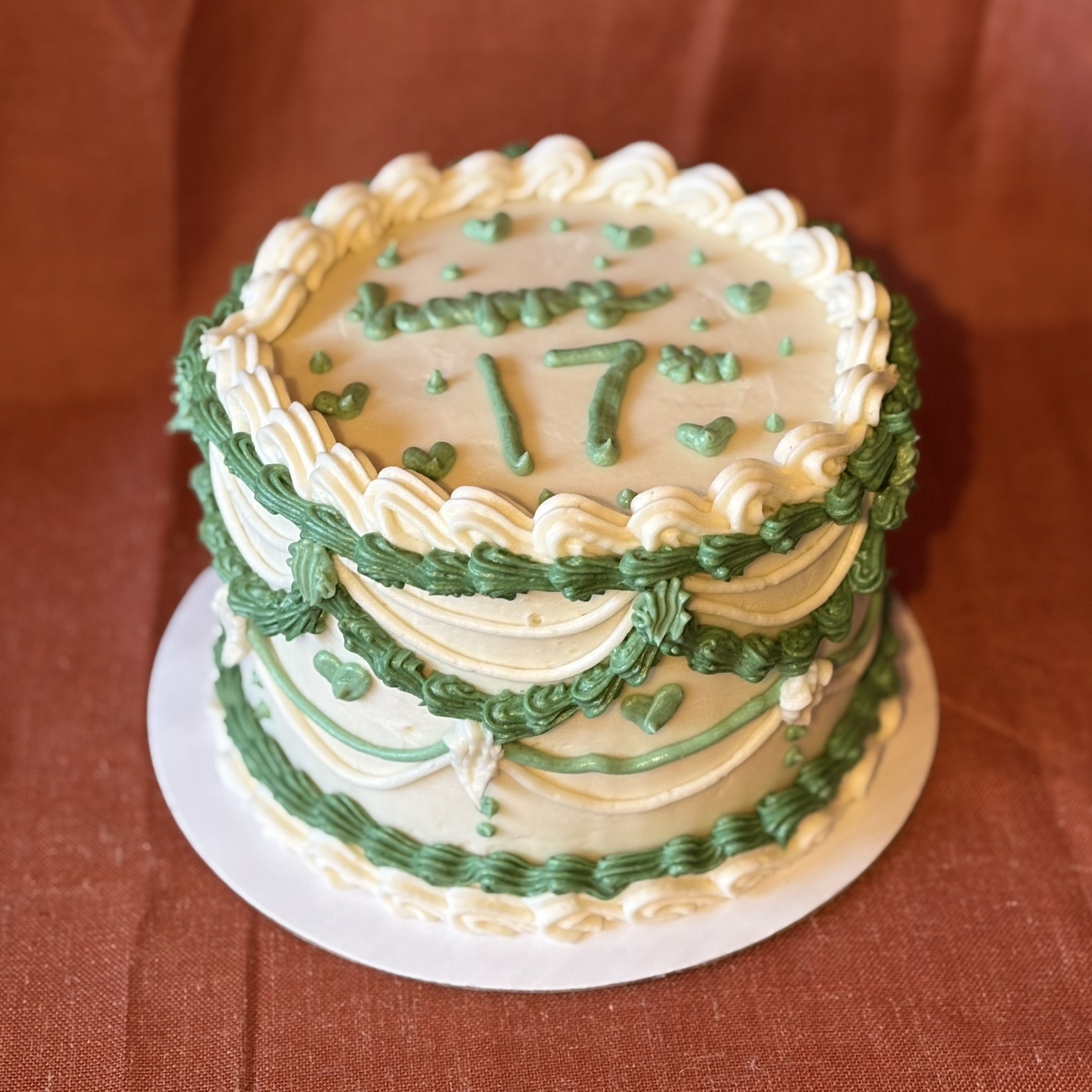A celebration cake decorated with white and green icing, featuring the number 17 on top.