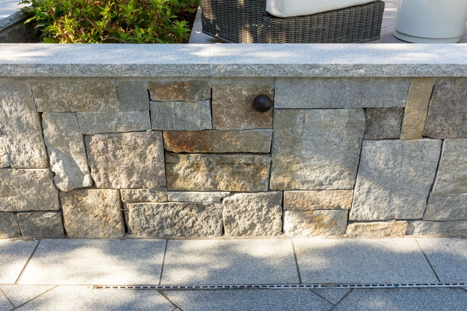 Stone retaining wall detail along raised patio in Newton, MA