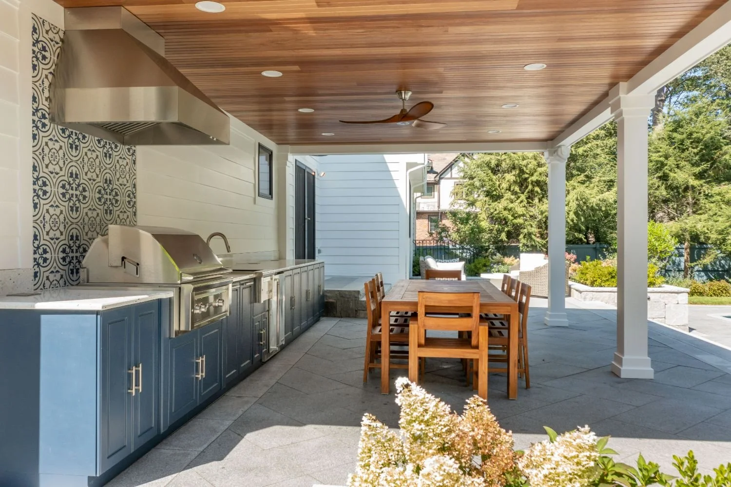 Outdoor kitchen beneath covered patio with dining table in Newton, MA
