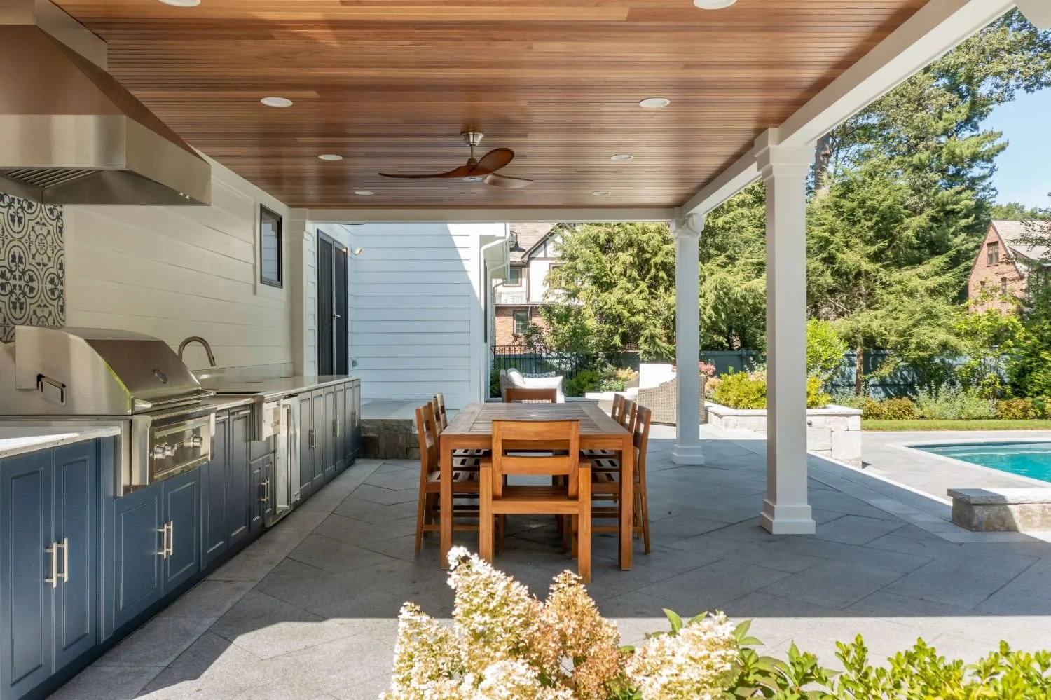 Covered outdoor kitchen and dining area overlooking the backyard in Newton, MA
