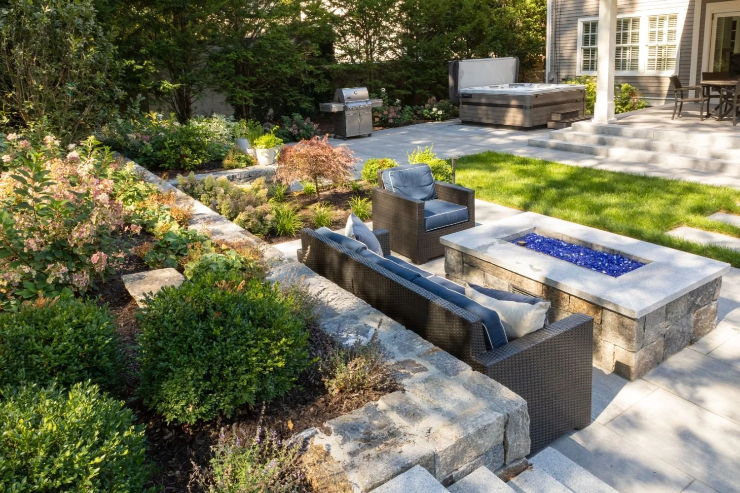 Raised patio with fire pit and outdoor lighting in Arlington, MA