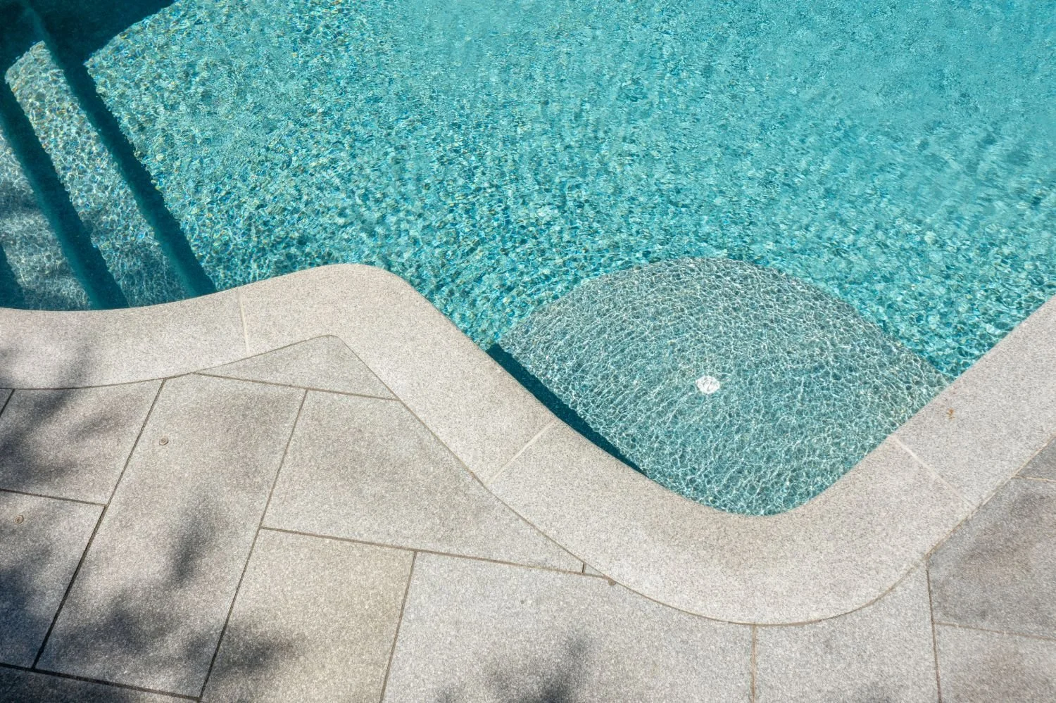 Pool deck edge with smooth stone coping and waterline in Newton, MA