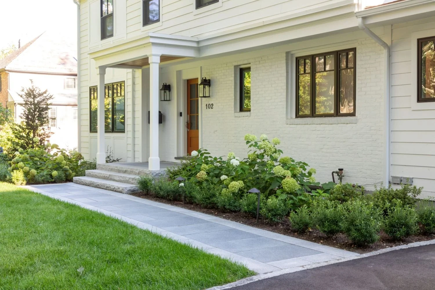 Stone retaining wall and garden beds shaping the yard in Newton, MA