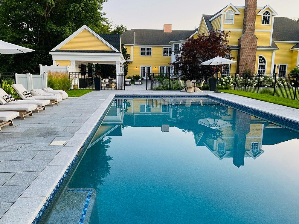 Modern pool deck with slip-resistant pavers at colonial home in Brookline, MA