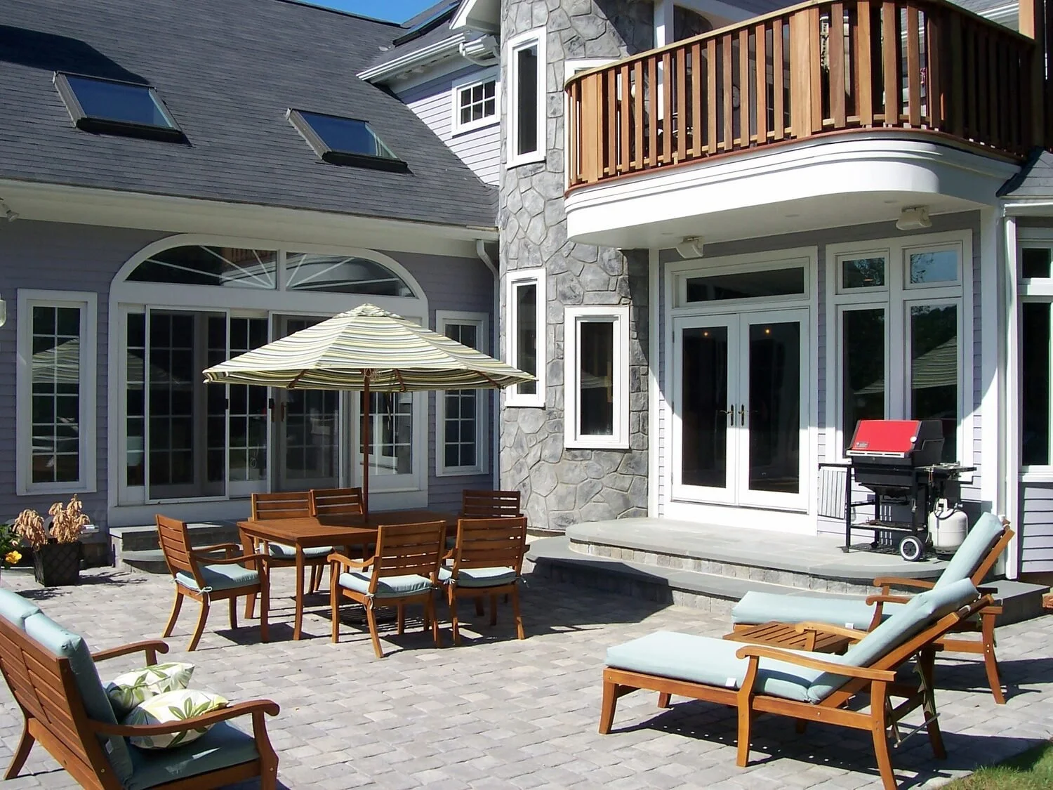 Backyard patio with seating area and a retaining wall built from natural stone in Concord, MA