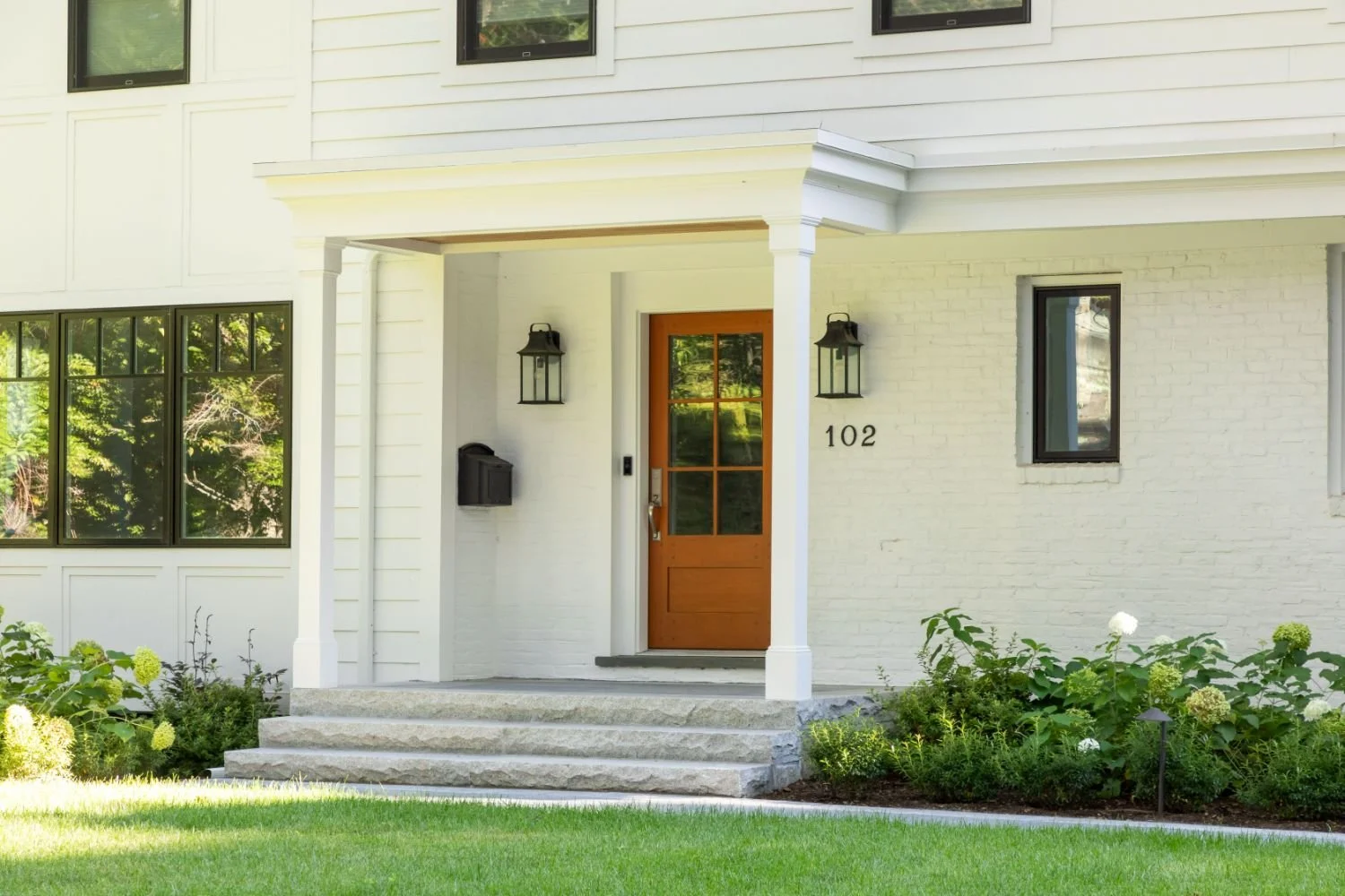 Landscape design integrating lawn, garden beds, and stone features in Newton, MA