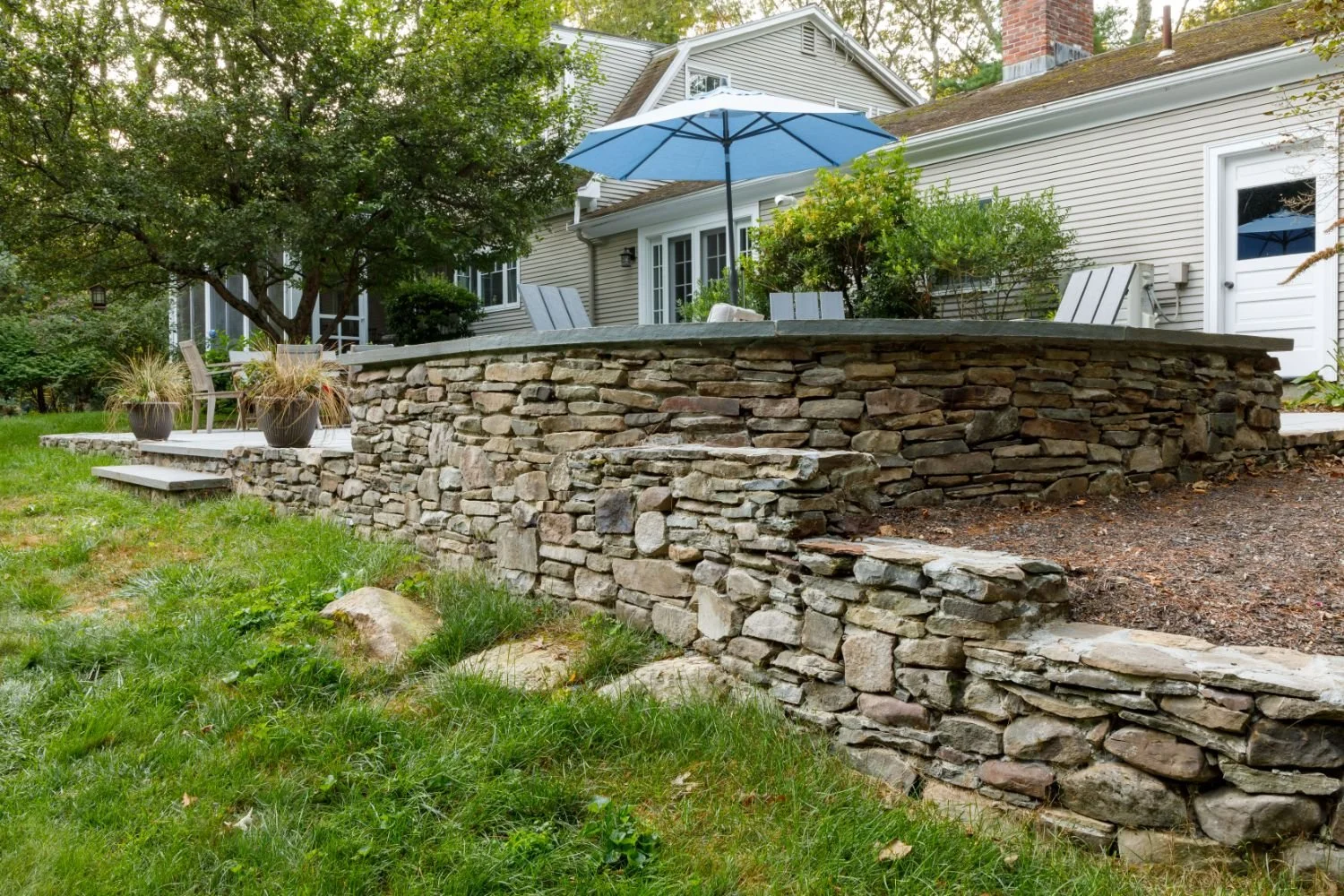 Elevated patio with stone walls and outdoor furniture in Lexington, MA