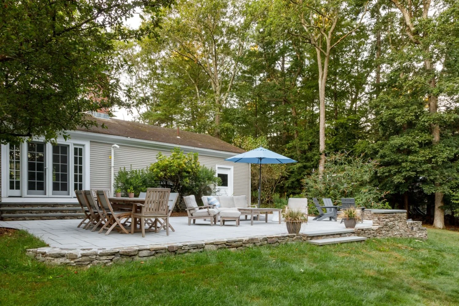 Backyard fire pit lounge with curved stone wall in Lexington, MA