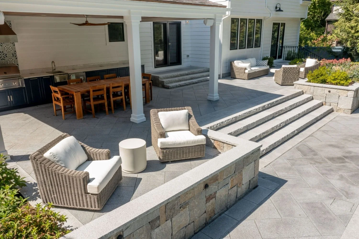 Raised patio with built-in seating and poolside lounge area in Newton, MA