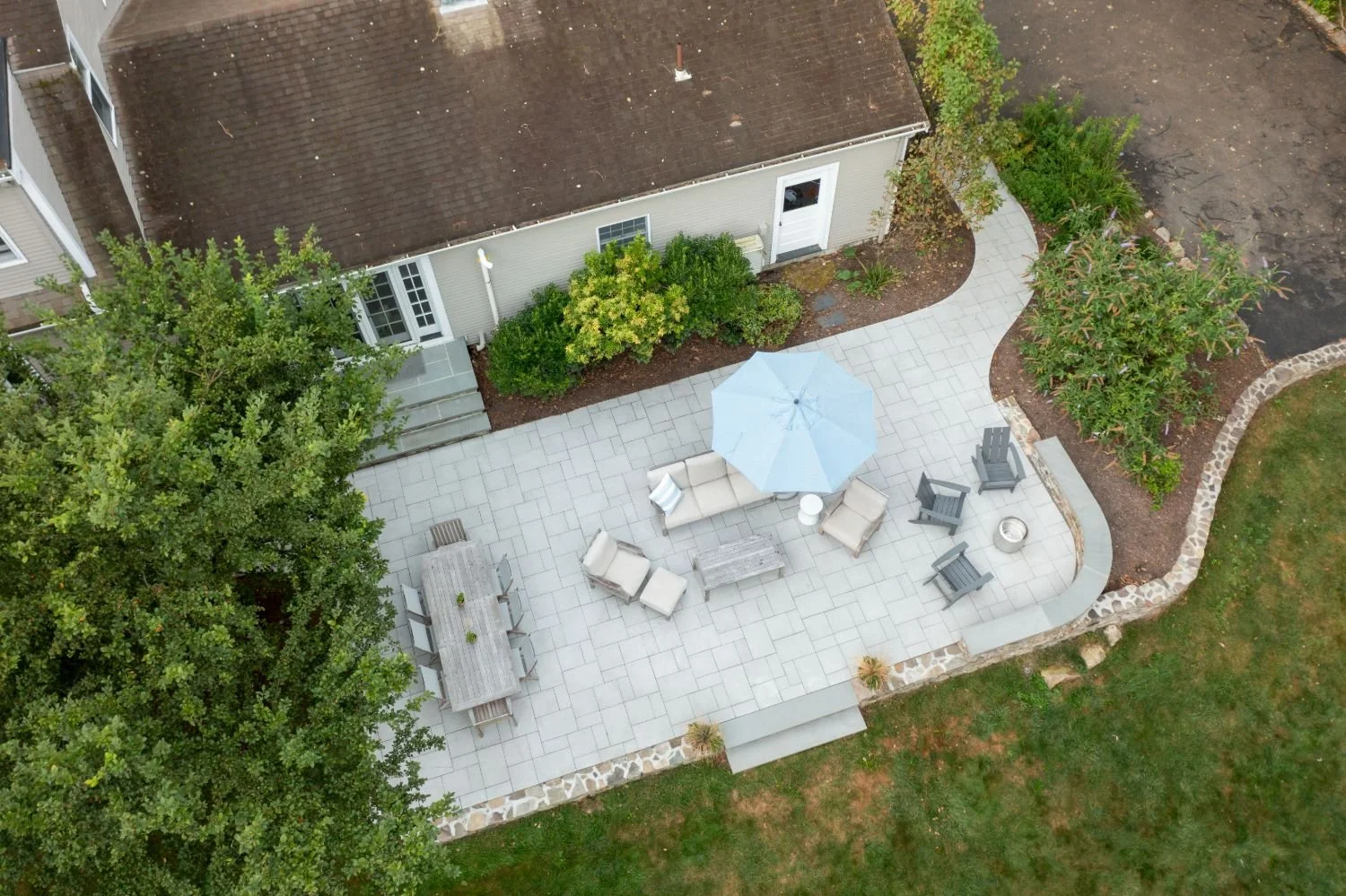 Backyard patio with stone retaining wall and layered seating areas in Lexington, MA