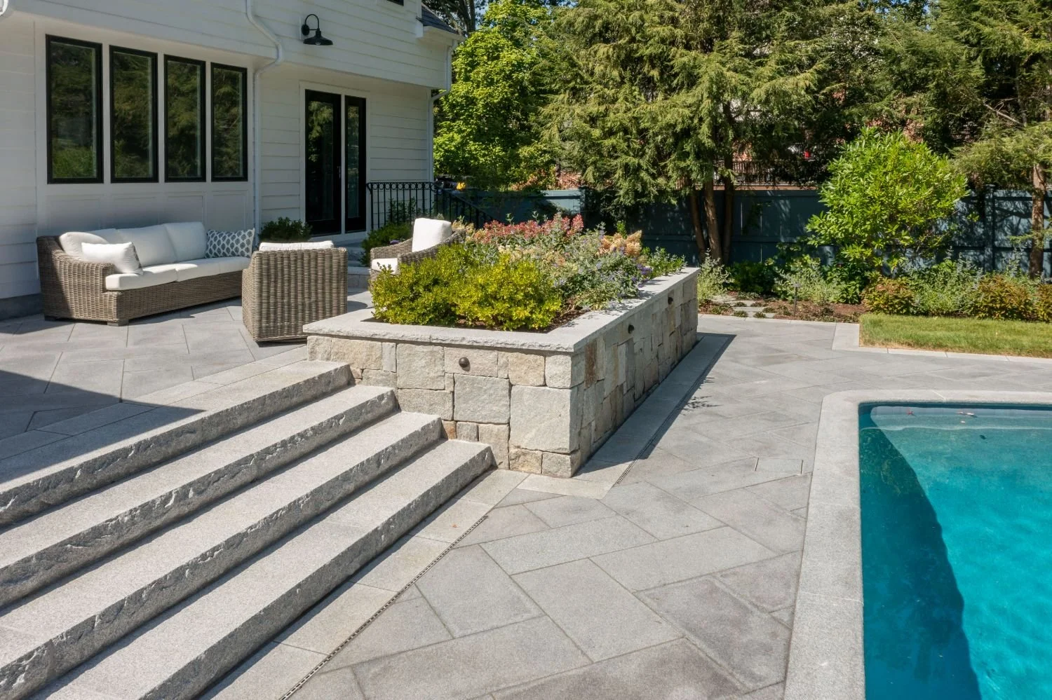Stone steps and raised planter integrated into patio design in Newton, MA
