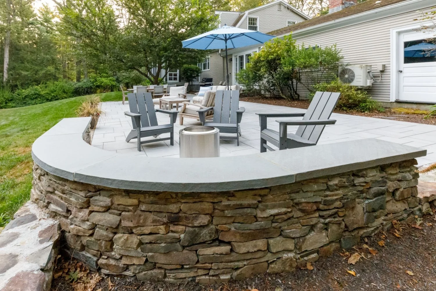 Stone patio and seating wall integrated into landscaped backyard in Lexington, MA