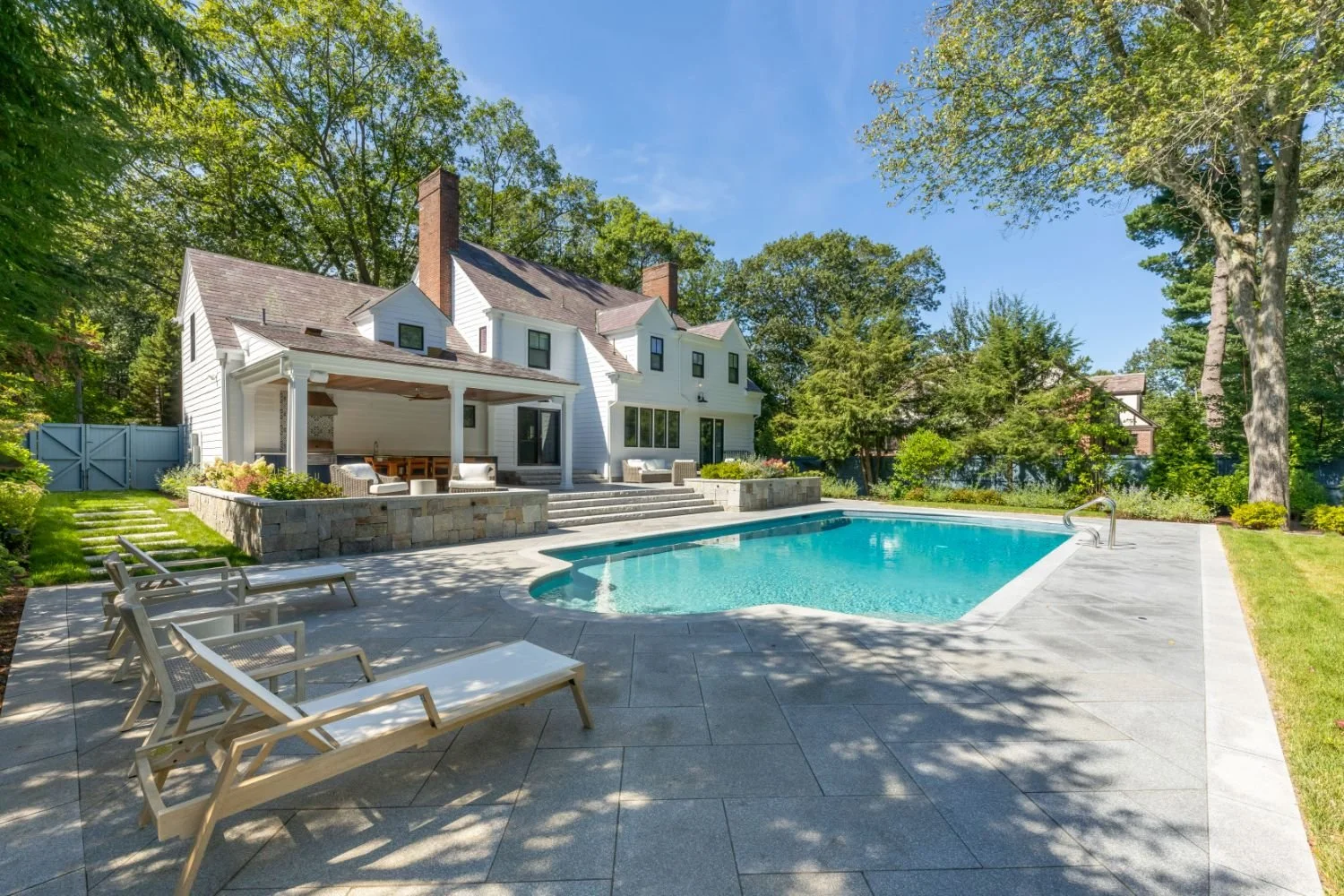 Pool deck with clean stone edges and surrounding outdoor living areas in Newton, MA
