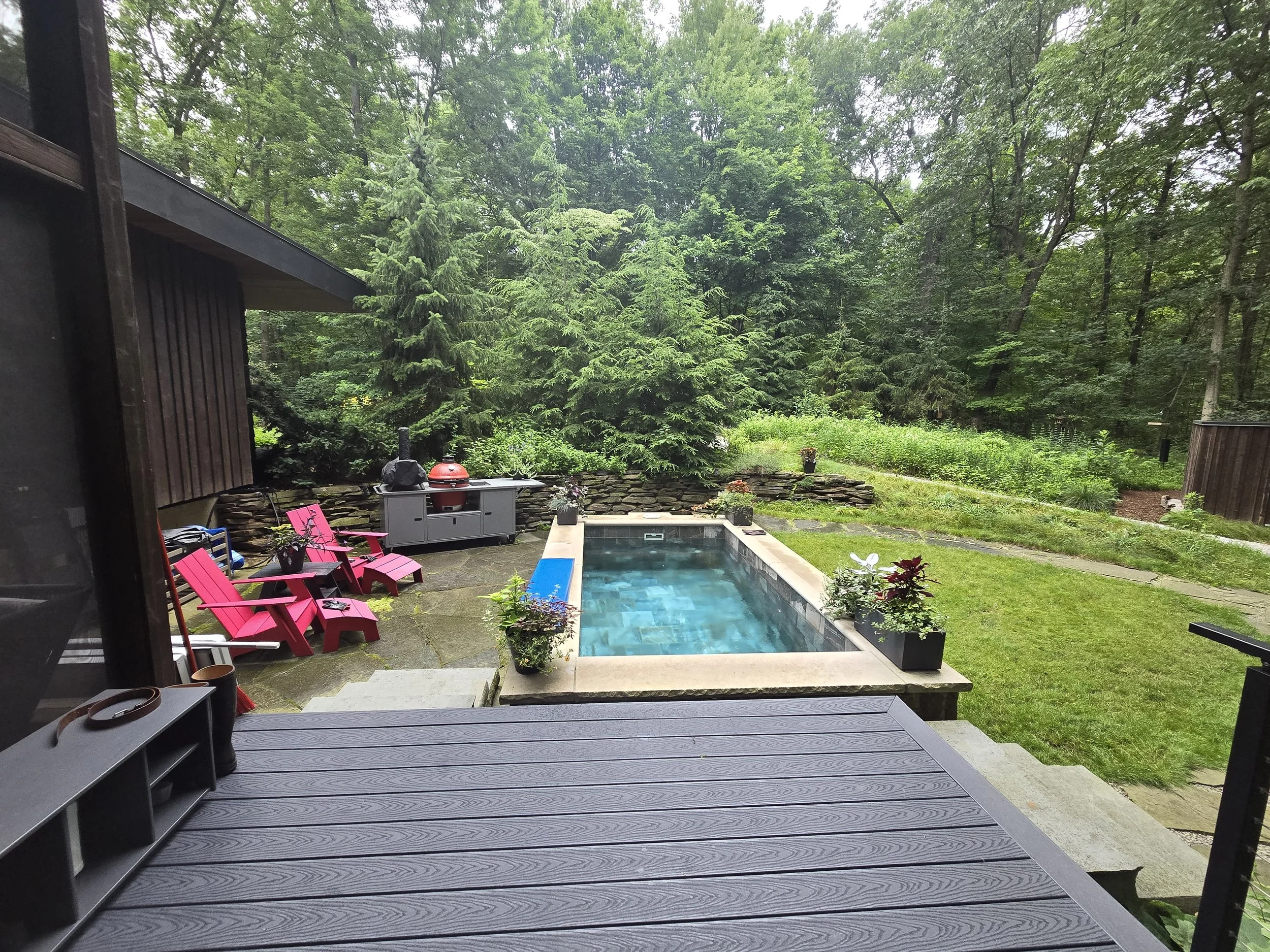 Backyard poolscape with peaceful waterfall and privacy plantings in Southwest Michigan