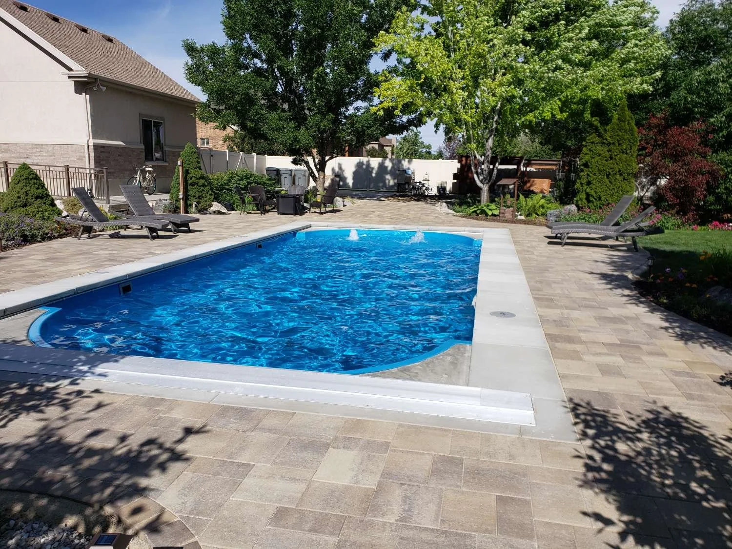 Fiberglass pool built for long-term durability with stone patio in Verona, WI