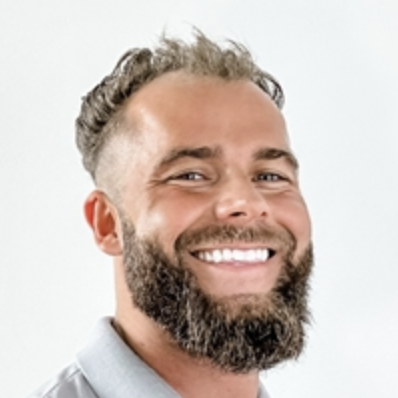 A smiling man with a beard and curly hair against a plain white background.