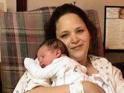 A woman holding a sleeping baby in her arms in a home setting.
