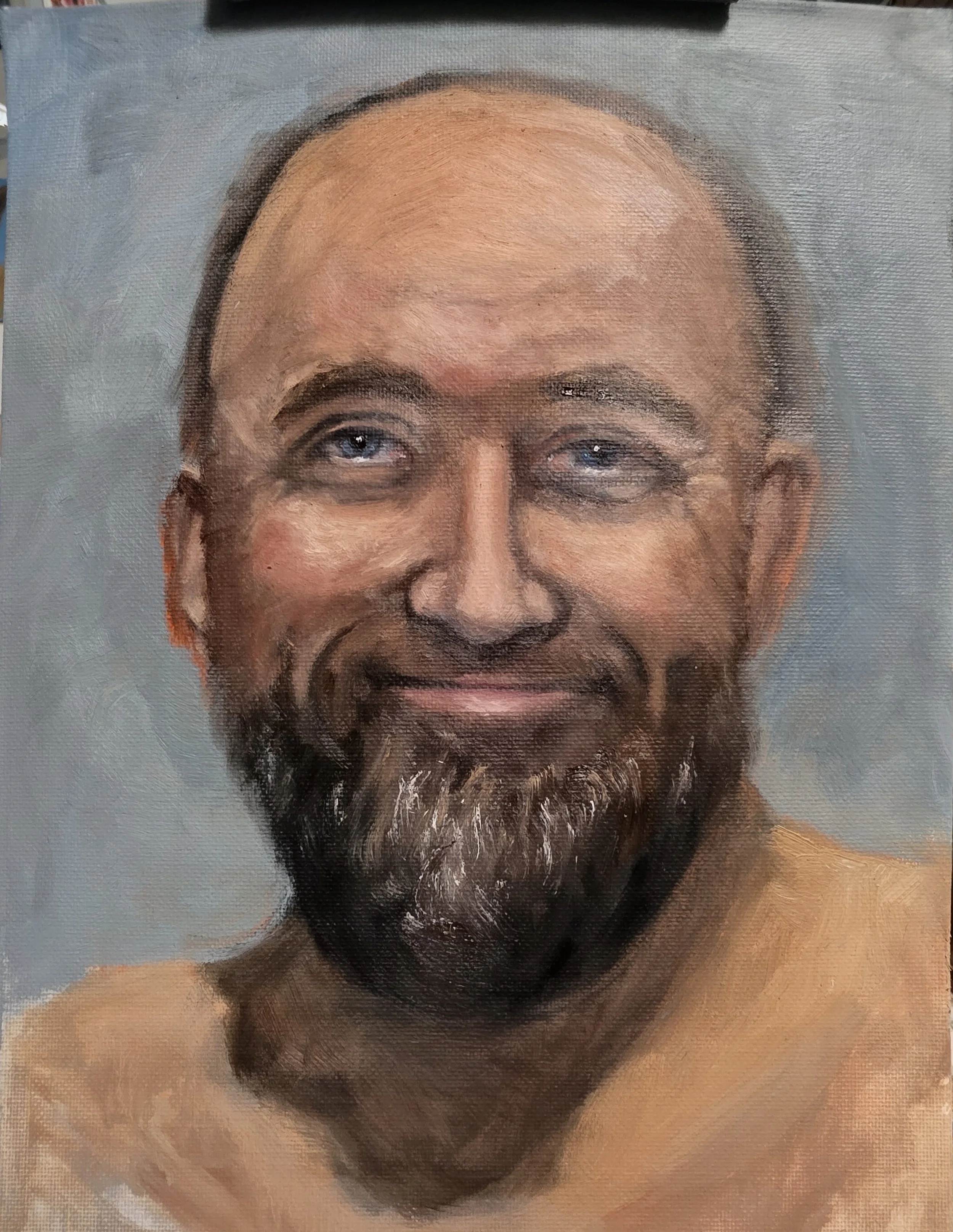 Close-up of a painted portrait of a smiling middle-aged man with blue eyes, a beard, and no shirt, against a plain background. Portrait of my husband David Armer