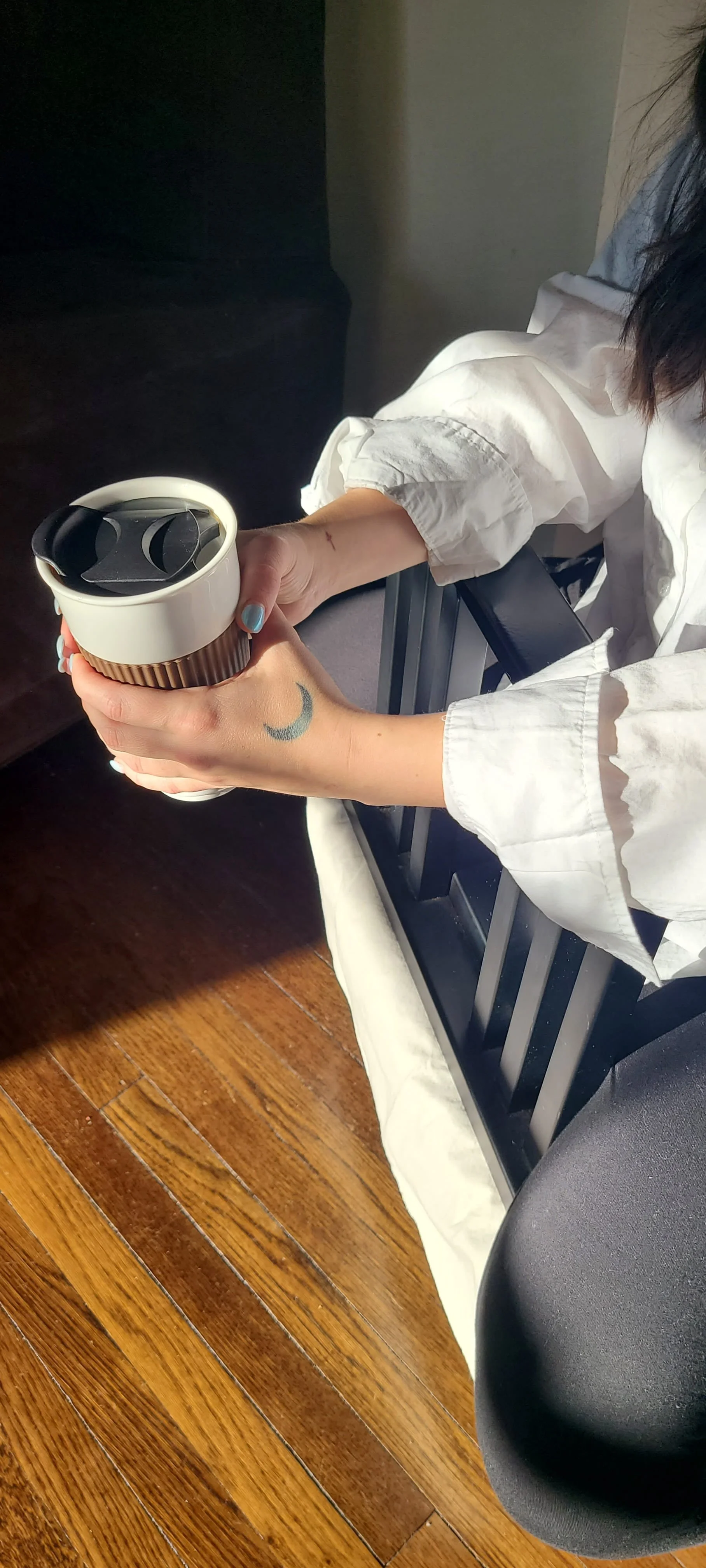 Tattooed hands holding a travel mug
