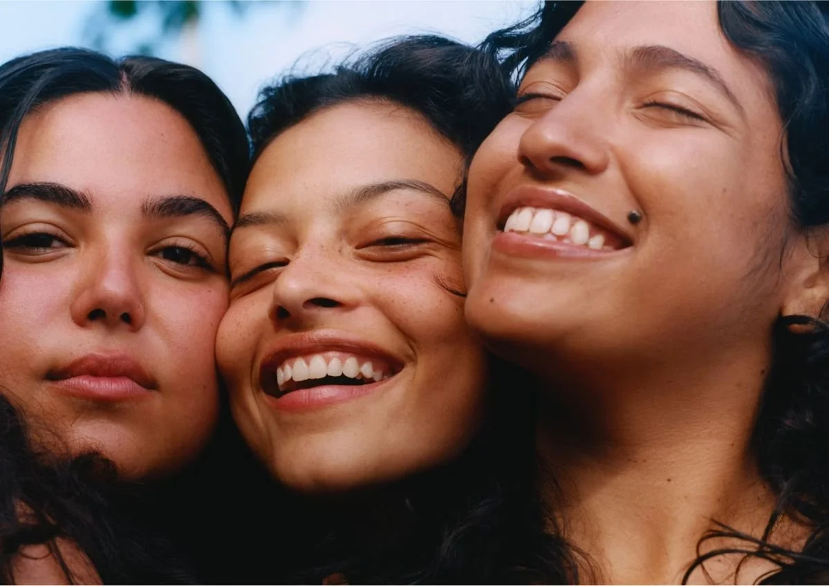 Three women taking a close-up selfie, smiling and enjoying each other's company.