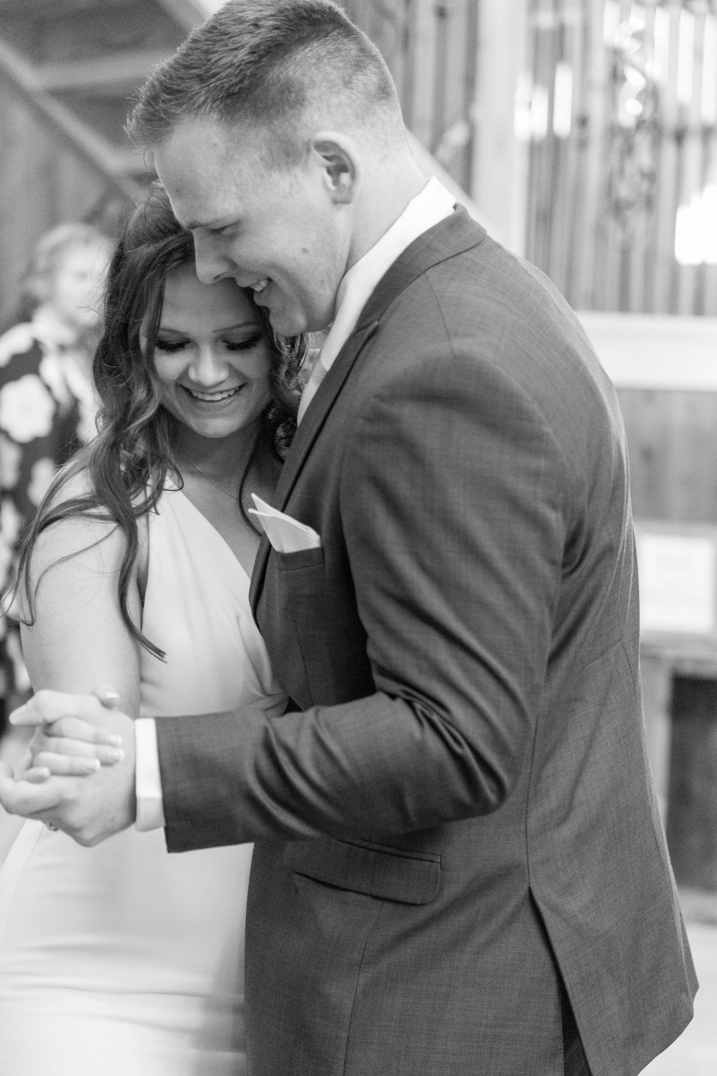 A black and white photo of a couple dancing closely, both smiling and enjoying a special moment together.