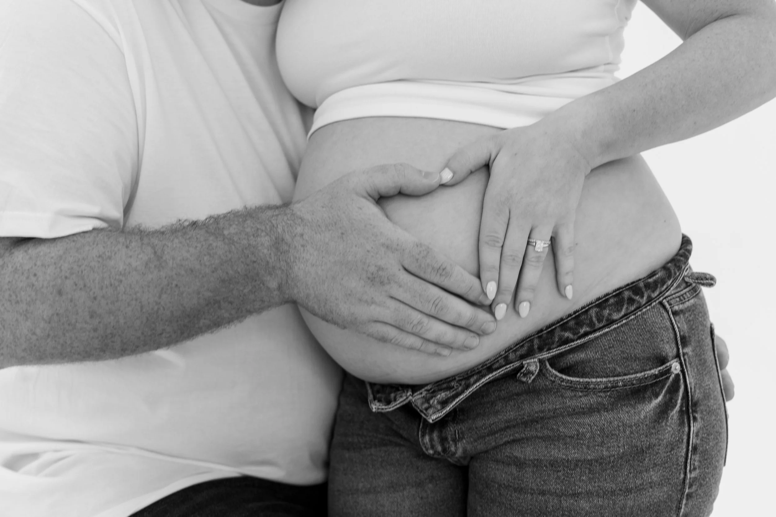 Close-up black-and-white photo of a person holding another person's arm, with both people wearing casual clothes.