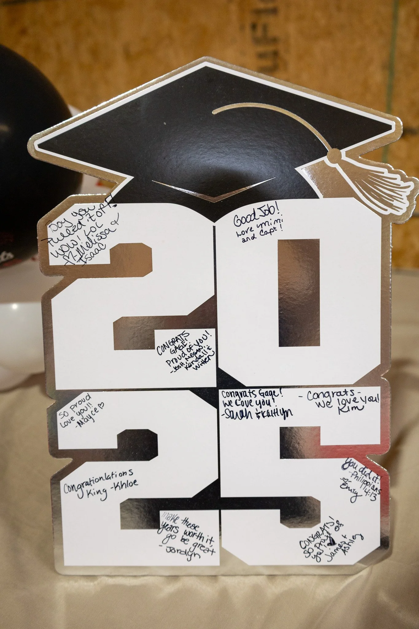 Graduation cap-shaped card with handwritten congratulatory messages and signatures.
