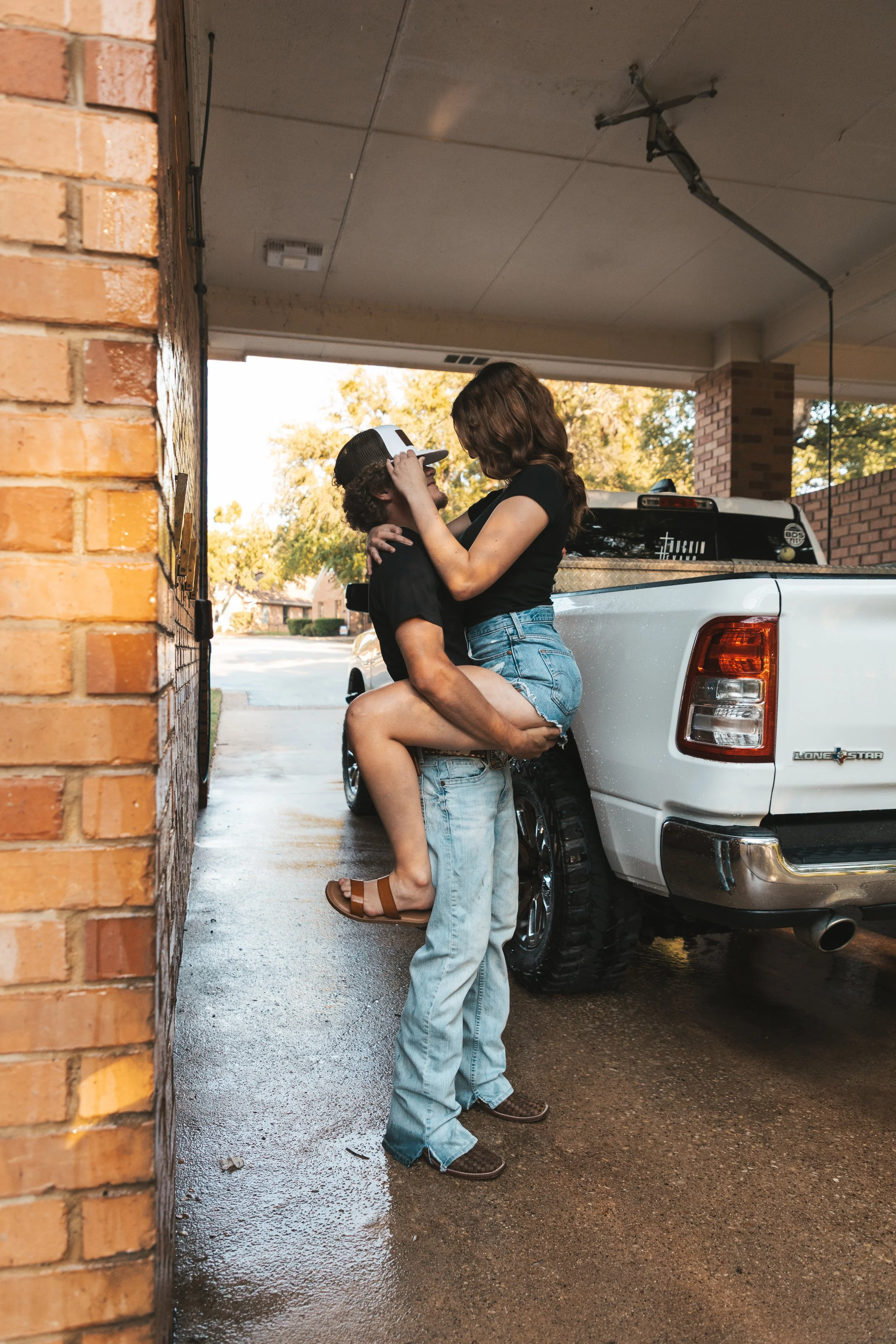 A man lifting a woman in a parking garage while they share an intimate moment.