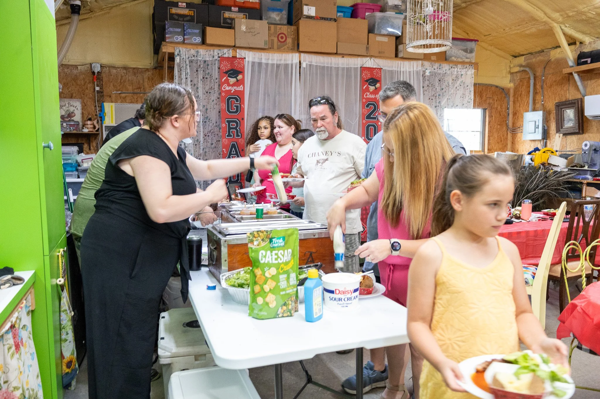 People serving themselves at a buffet table during a graduation celebration.