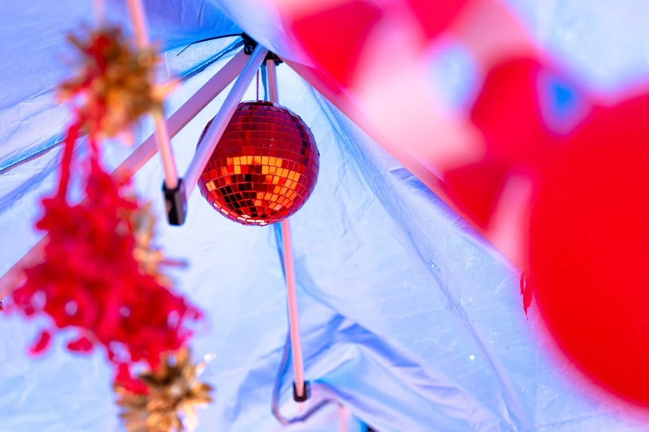 Red disco ball hanging inside a tent with festive decorations in the foreground