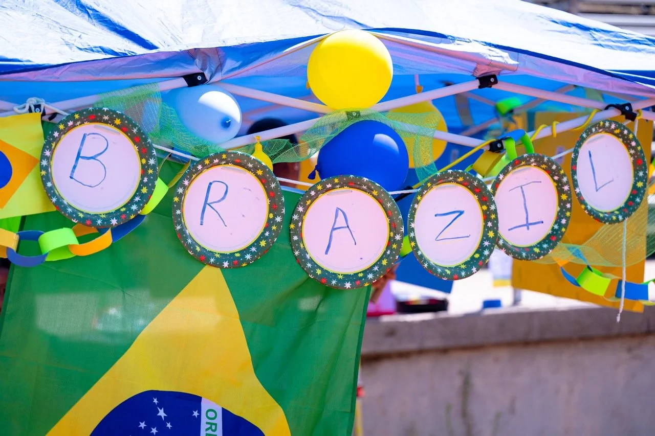Decorated booth with balloons, paper chains, and a banner displaying the message 'B R A Z I L' for a celebration, featuring a Brazilian flag.
