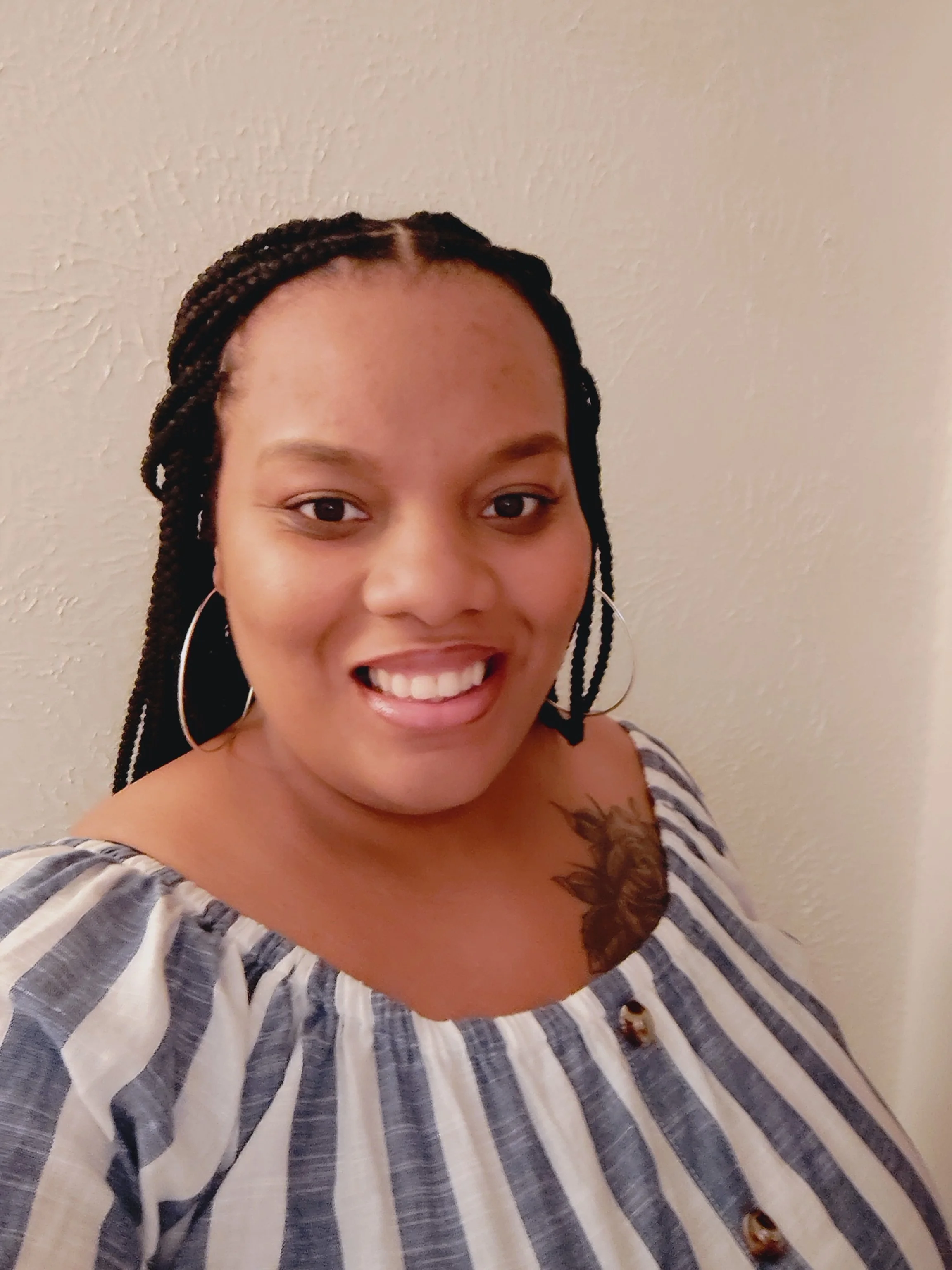 Smiling person with braided hair in a striped shirt.