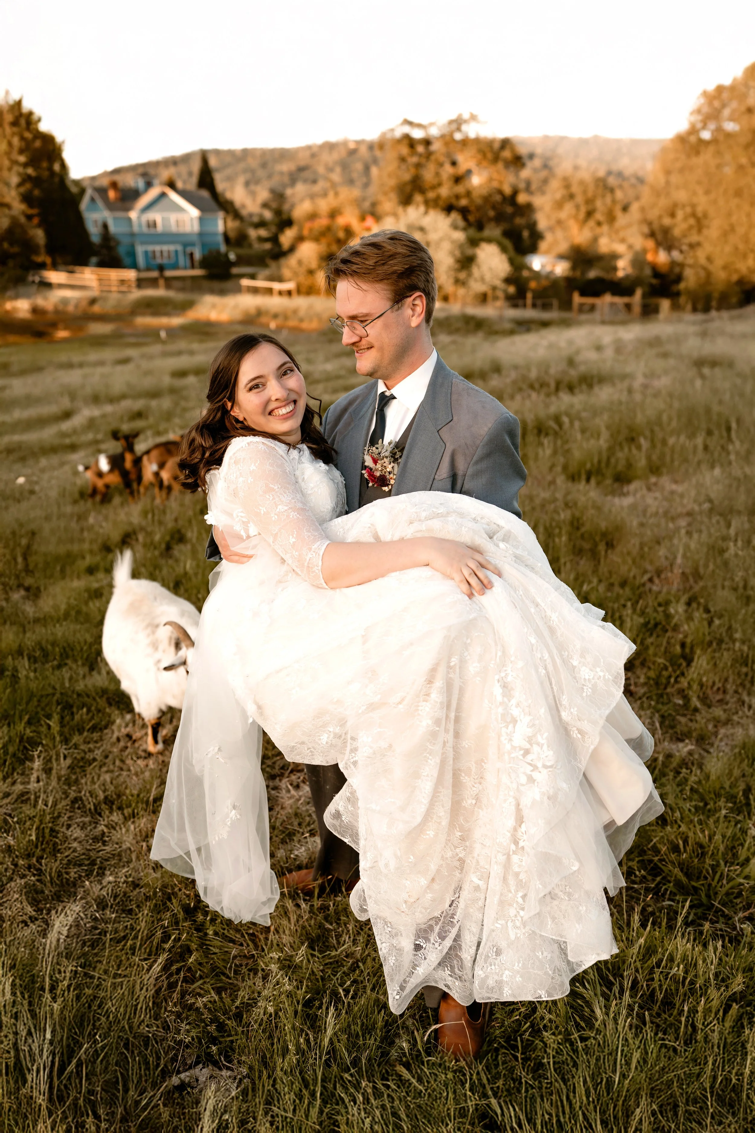 A couple stands close together outdoors in a field with cows in the background. The man wears a brown hat, white shirt, and suspenders. The woman has a leather jacket with floral embroidery and a message that reads, 'It was always you.'