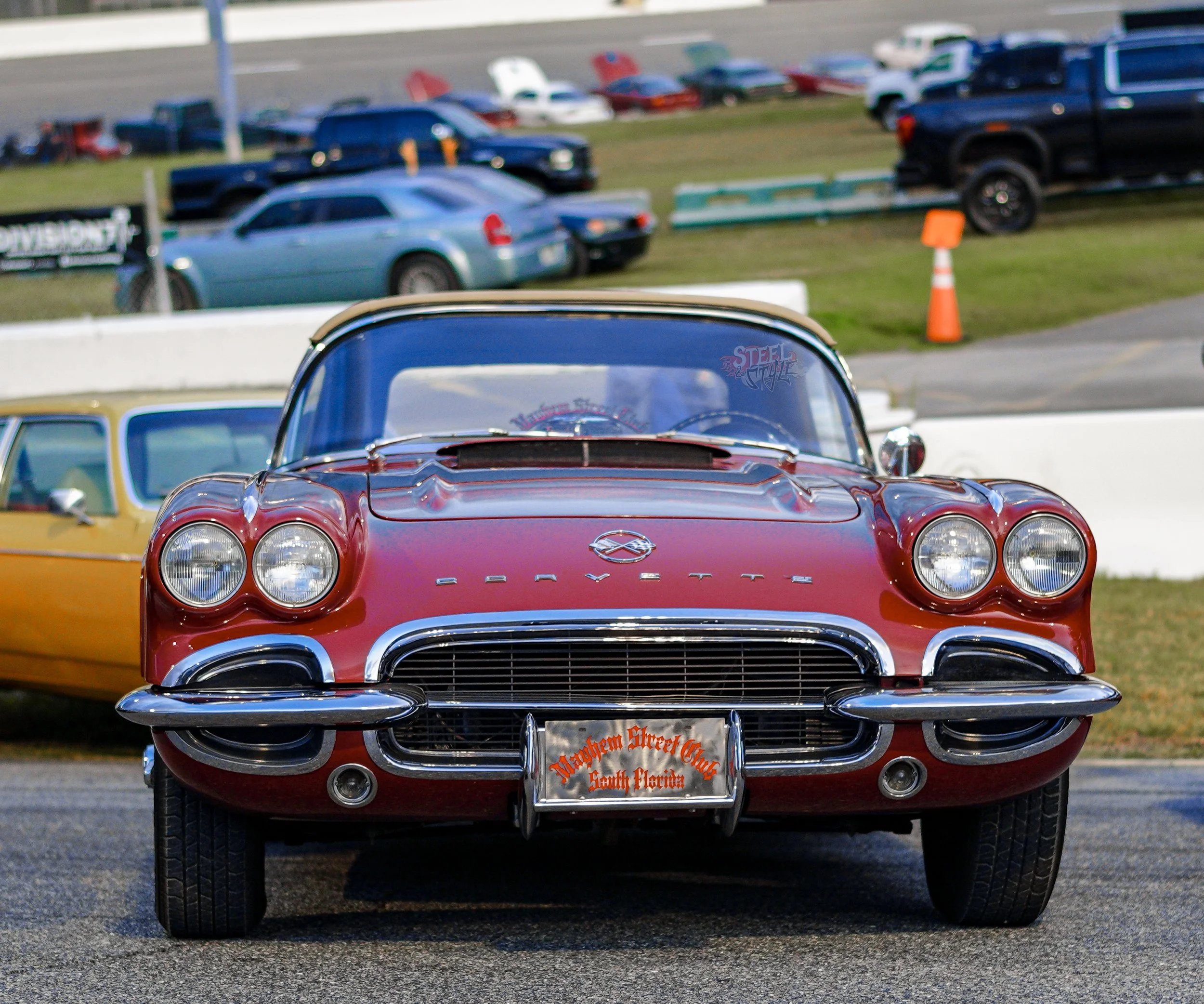 Red vintage Corvette with chrome bumper and Princeton Street Club license plate at a car show.