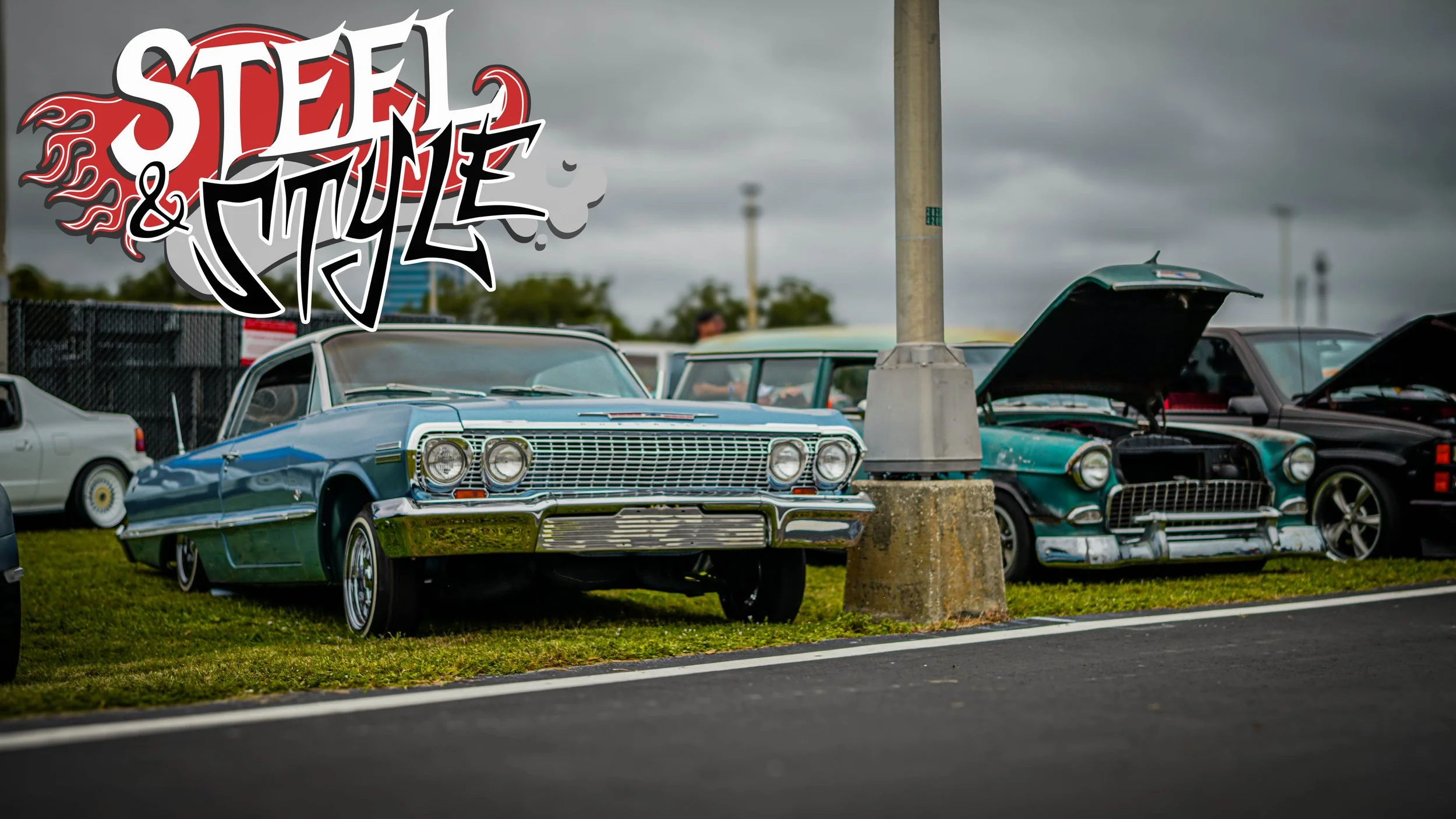 A row of vintage cars parked on grass at a car show, with a stylized "Steel & Style" logo in the top left corner.