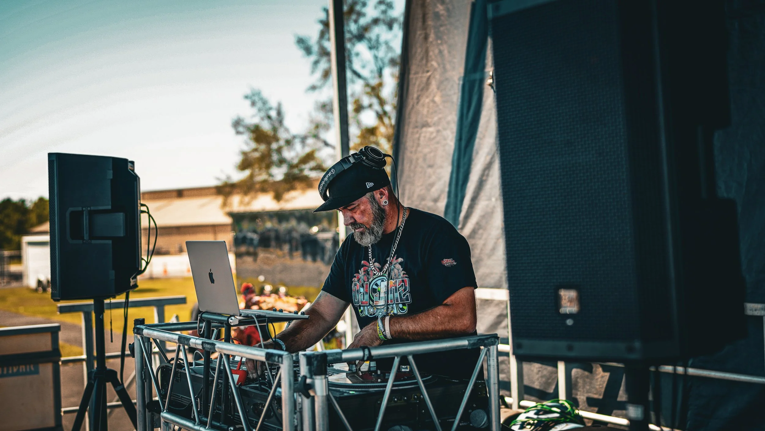 DJ performing at an outdoor event with music equipment and speakers.