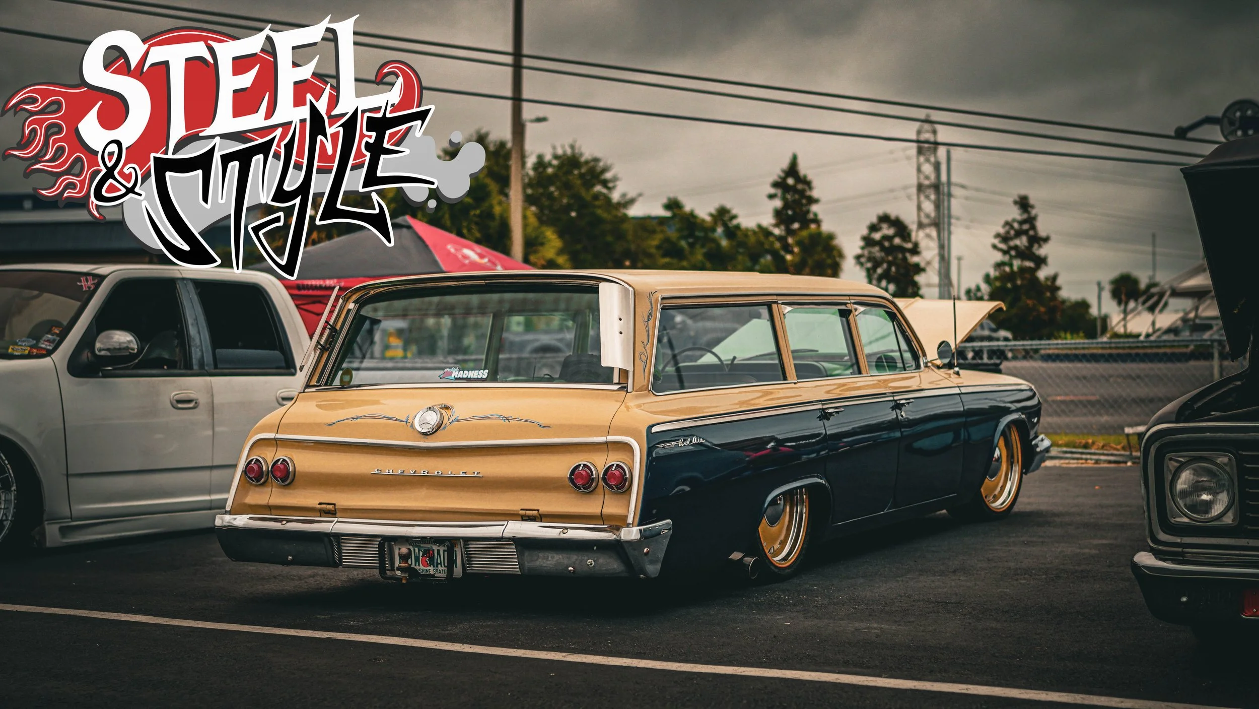 A vintage Chevrolet station wagon with custom paint in black and beige, parked among other classic cars at a car show on a cloudy day.