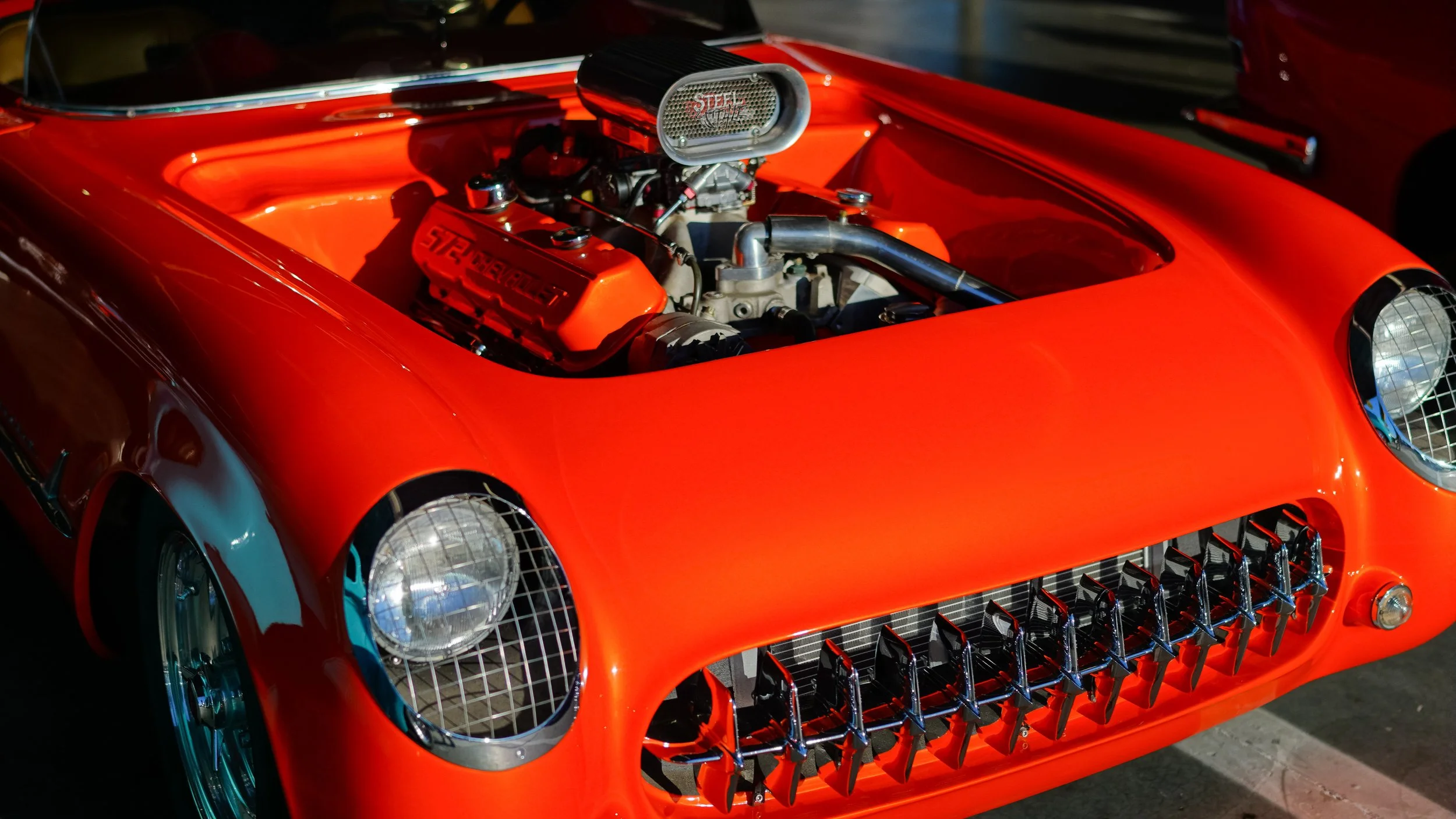 Close-up of a vintage red race car with exposed engine and grille.