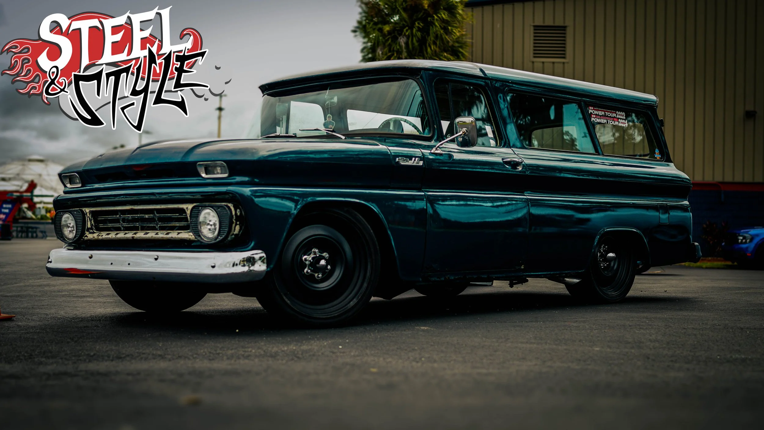 A vintage blue and black panel van parked outdoors, with a graffiti-style logo labeled 'Steel & Style' in the top left corner.
