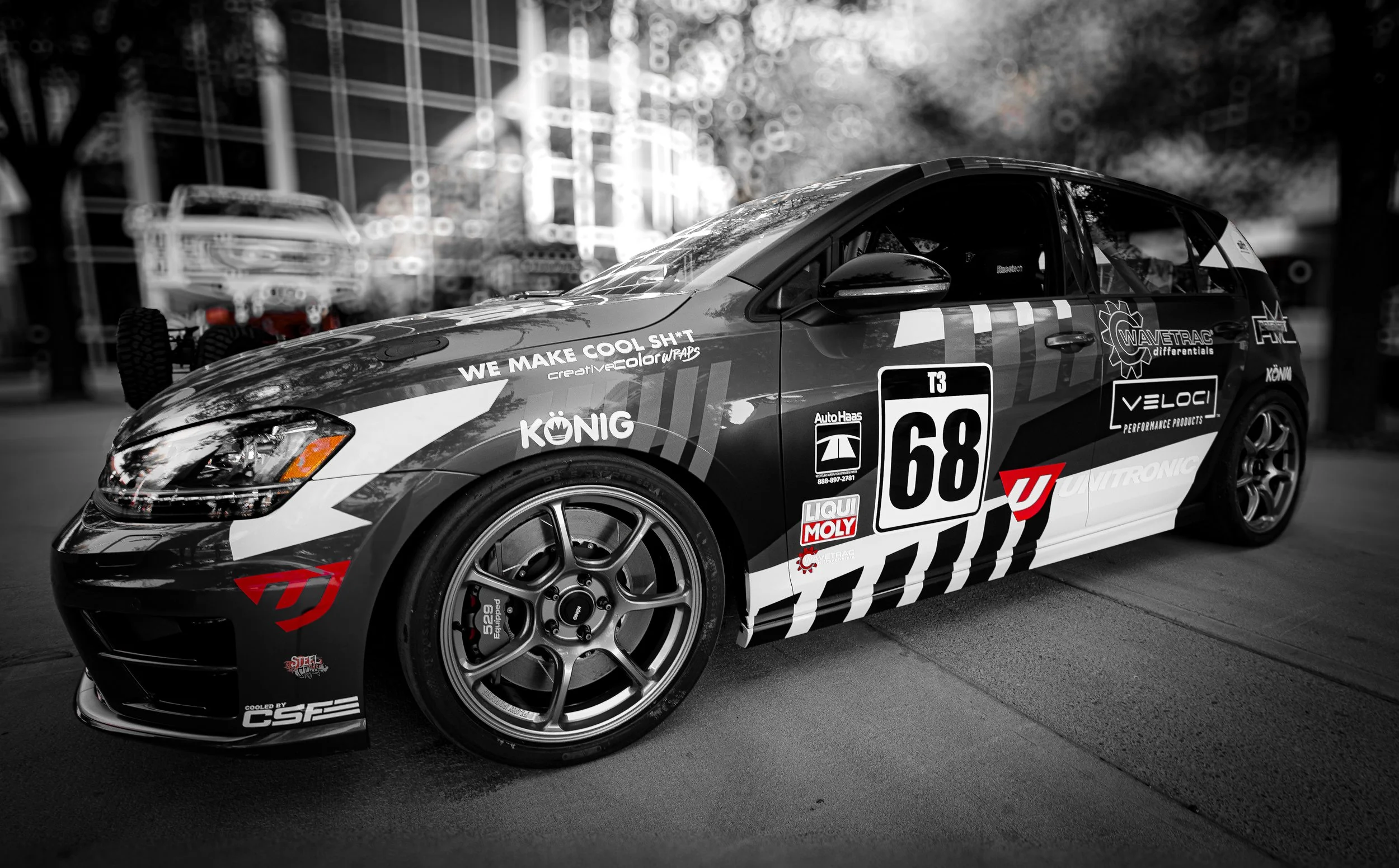 Black and white racing car with various sponsor decals and the number 68, parked on the street.